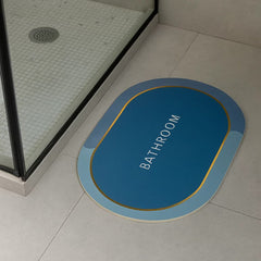 Tapete de baño ovalado azul 40×60 cm “BATHROOM” borde dorado vista frontal