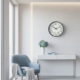 Reloj de pared redondo con números negros y marco color marrón claro