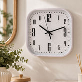 Reloj de pared cuadrado blanco con números negros y manecillas negras