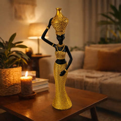 Figura decorativa mujer africana con jarrón dorado en la cabeza y brazo en la pierna