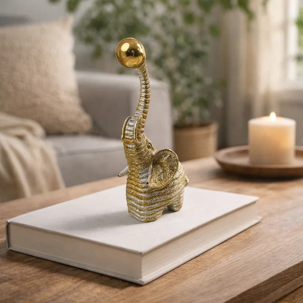 Elefante decorativo dorado con balón en la trompa