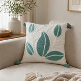 Cojín decorativo blanco 45×45 cm con hojas verdes texturizadas y borlas en las esquinas
