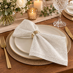 Servilleta de tela beige de 45 × 45 cm con diseño floral ornamental, acabado satinado y bordes festoneados.