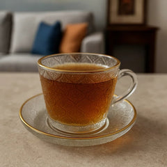 Set de té de vidrio con diseño floral y borde dorado, incluye taza y plato.