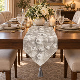 Camino de mesa gris plata y blanco con diseño floral y borla decorativa.