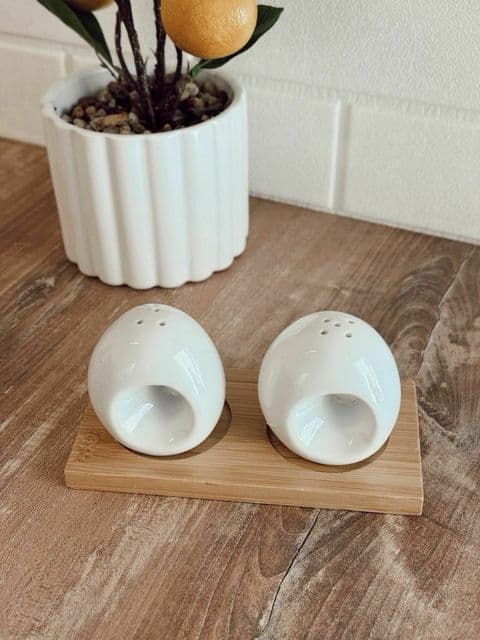 Set de saleros ovalados blancos sobre base de madera