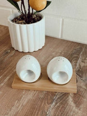 Set de saleros ovalados blancos sobre base de madera