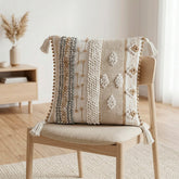 Cojín Elite Herencia 323 natural 45×45 cm con texturas en relieve, franjas tejidas y borlas decorativas