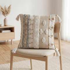 Cojín Elite Herencia 323 natural 45×45 cm con texturas en relieve, franjas tejidas y borlas decorativas