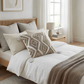 Cojín Rustic Boucle 157 marfil 45×45 cm con textura bouclé, rombos en relieve y borlas sobre cama