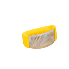 Machacador de ajo acero inoxidable con recubrimiento de silicona verde en tabla de cocina.