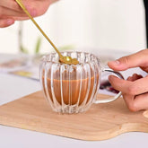 Pocillo de vidrio transparente con doble pared y diseño de líneas verticales, servido con café.
