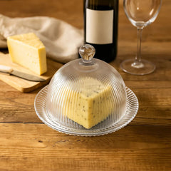 Recipiente tipo domo en vidrio con diseño de líneas verticales sobre base transparente.