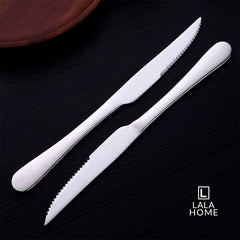 Set de 6 cuchillos de acero inoxidable plateados con filo dentado sobre fondo oscuro.