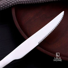 Set de 6 cuchillos de acero inoxidable plateados con filo dentado sobre fondo oscuro.