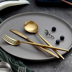 Set de 6 cucharas doradas New York sobre plato gris – diseño elegante.