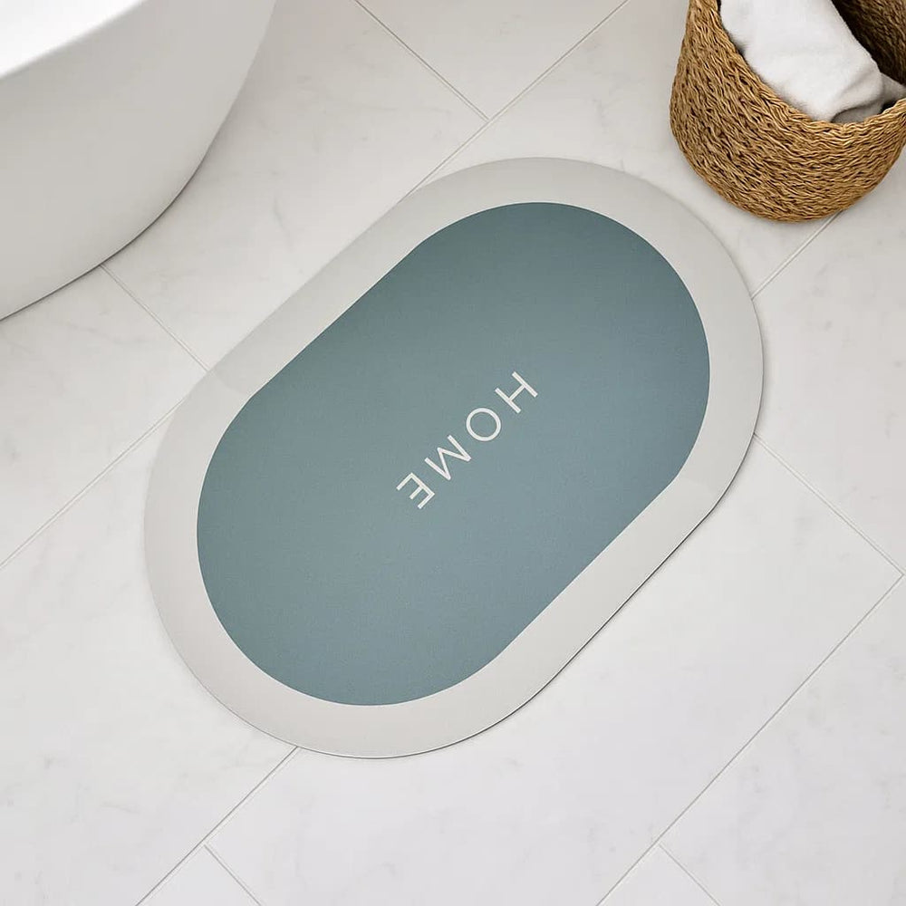 Tapete de baño ovalado 40×60 cm gris‑azulado “HOME” vista frontal