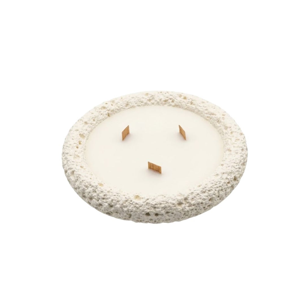 Vela artesanal circular blanca con textura tipo piedra