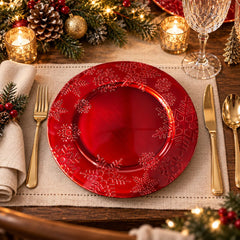 Plato base navideño de melamina rojo brillante con copos de nieve decorativos alrededor del borde.