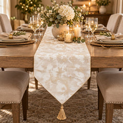 Camino de mesa oro rosa y blanco con diseño floral y borla decorativa.