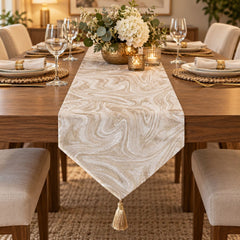 Camino de mesa blanco y oro rosa con diseño marmoleado y borla decorativa.