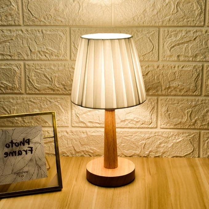 Lámpara de escritorio nórdica de 29 cm con pantalla blanca de tela plisada y base en bambú sobre mesa de madera.