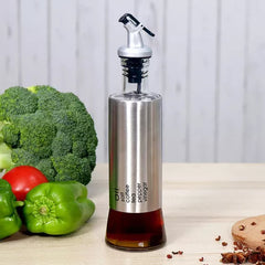 Vinagrera de vidrio de 300 ml con acabado gris plata y tapa dispensadora antigoteo sobre mesa de cocina.